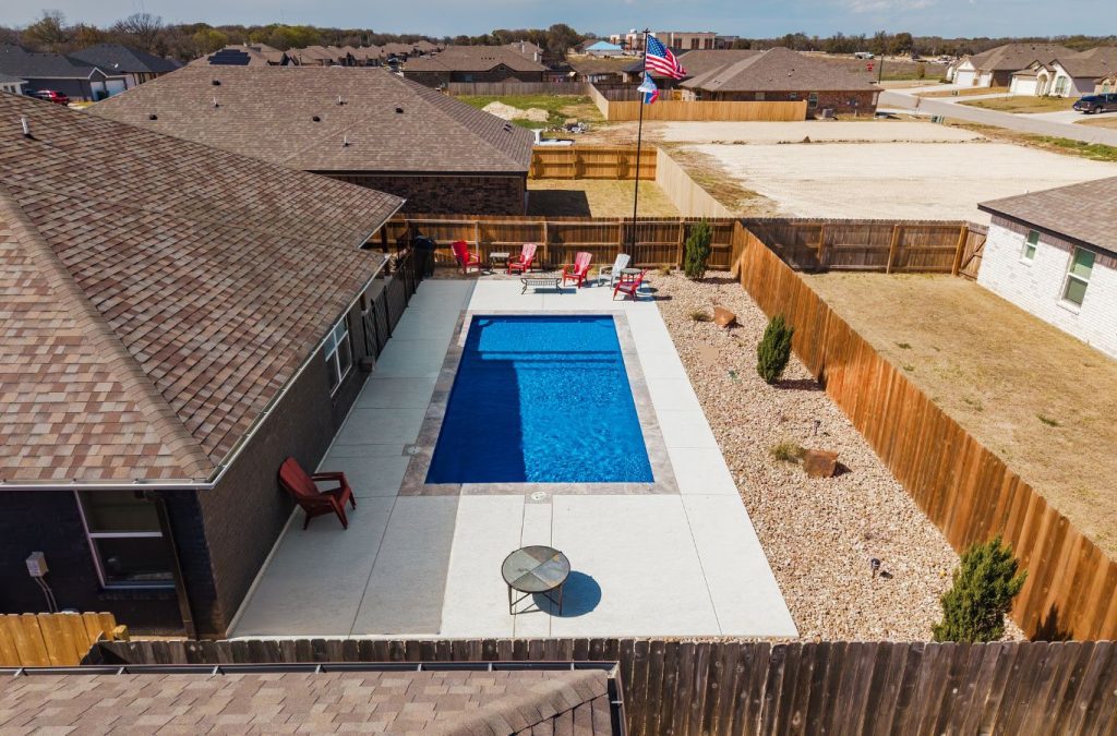 A POOL-ology team member showcasing a clean, energy-efficient fiberglass pool build in Heatherwilde, TX backyard.