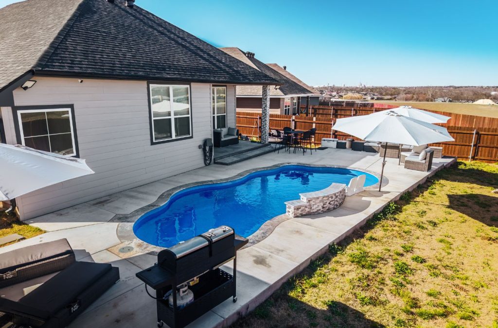 POOL-ology expert completing fiberglass pool construction in Heatherwilde, TX, with a sleek patio and outdoor setup.