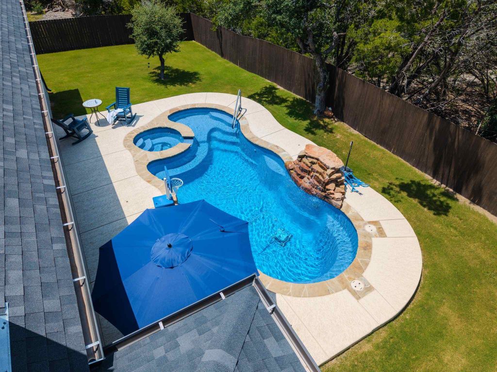 A beautiful, newly installed quality fiberglass pool by POOL-ology, the centerpiece of a serene Austin, TX backyard