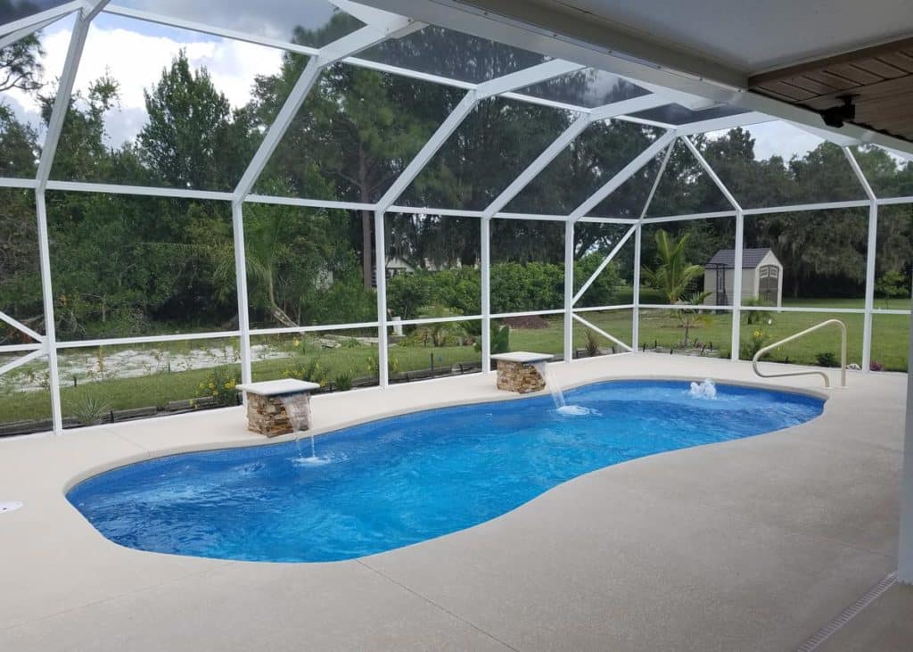 Vista Isle fiberglass pool, freeform design with dual bubbler fountains under screen enclosure