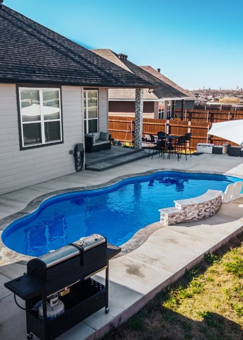POOL-ology expert completing fiberglass pool construction in Heatherwilde, TX, with a sleek patio and outdoor setup.